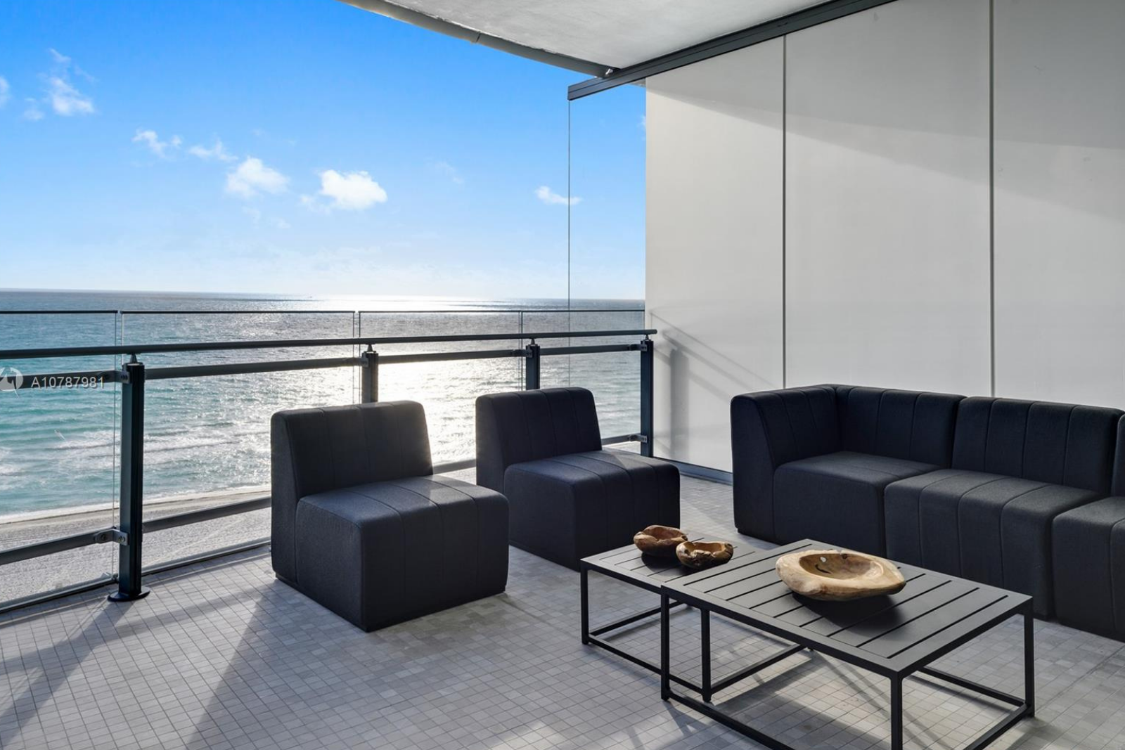 an outdoor furniture set up with black chairs and a black couch overlooking Miami beach